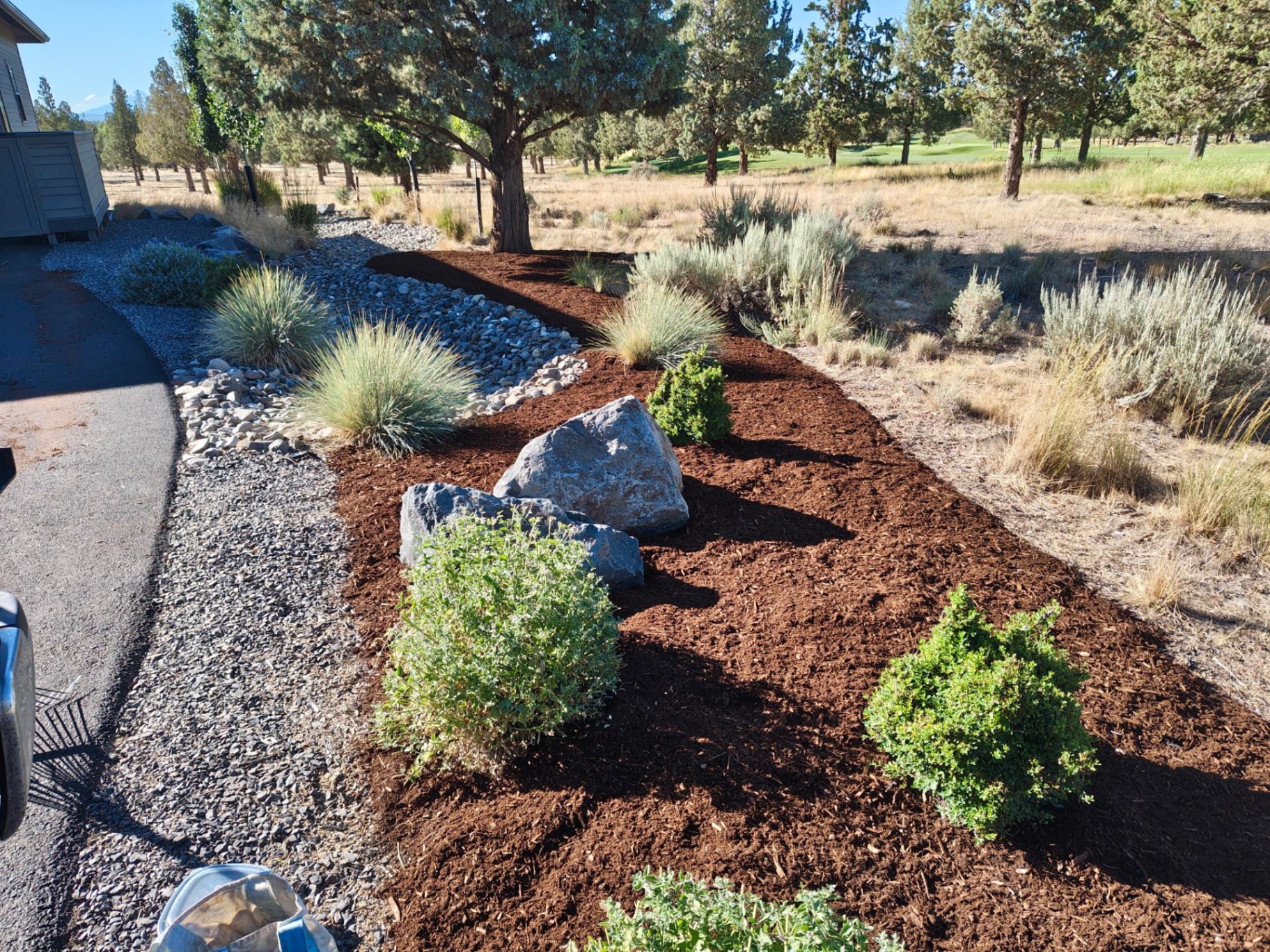 Dry creek bed with river rock, boulders and drought-tolerant mulch landscape beds in Bend Oregon in Sunriver, OR by A1 Lawn & Landscape of Bend