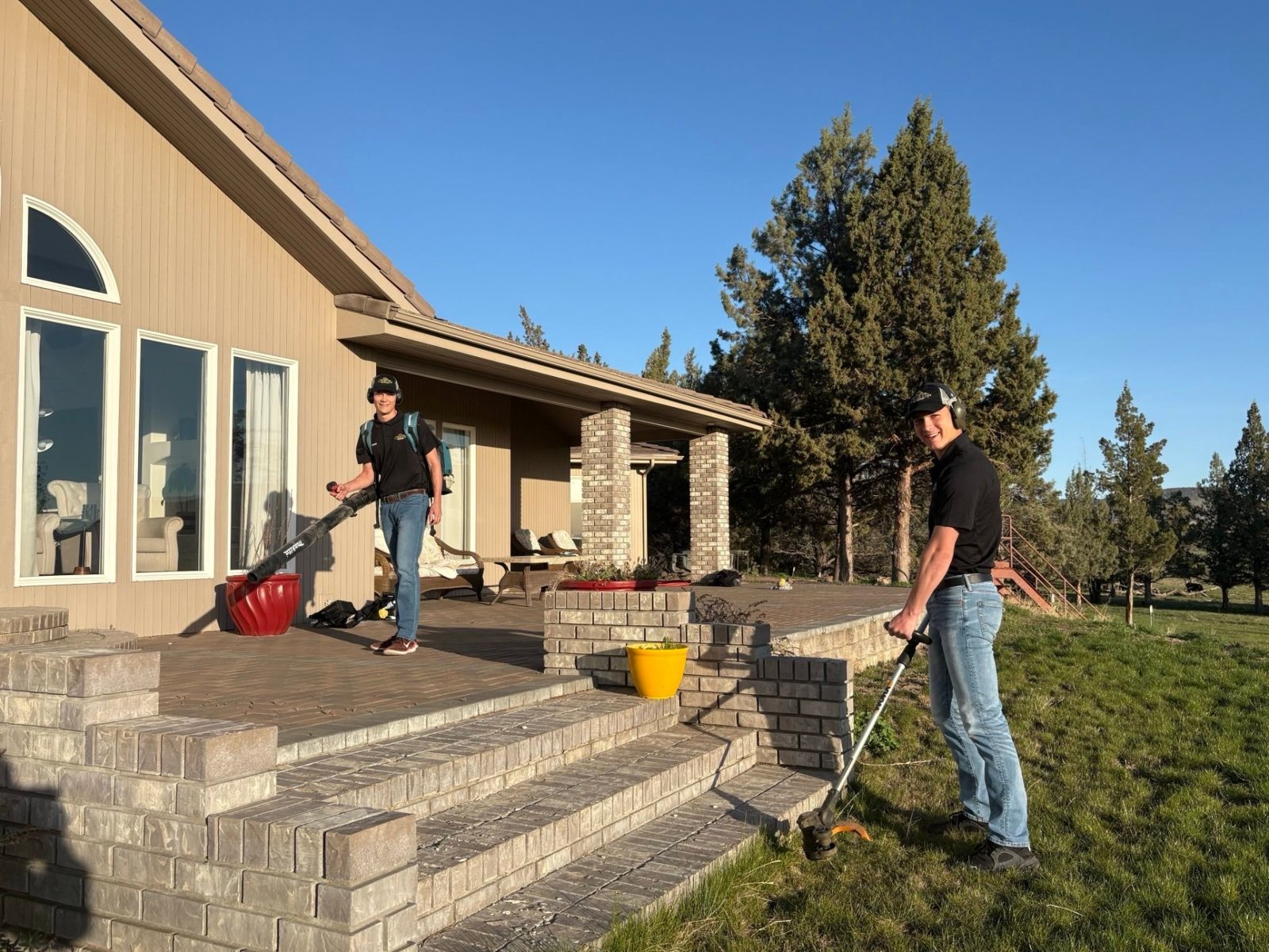 A1 crew handling a spring yard cleanup with blower and string trimmer at a Central Oregon home in Sunriver, OR by A1 Lawn & Landscape of Bend